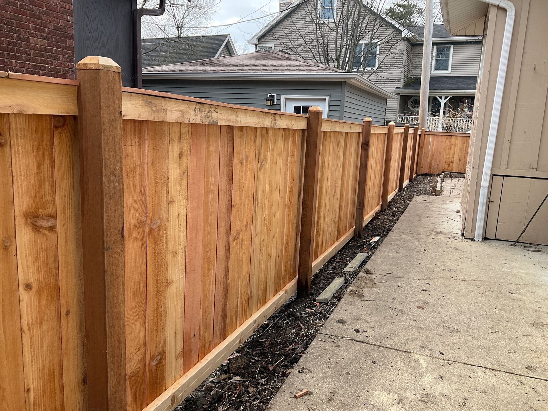 Wooden fence along a paved alleyway, next to a building.