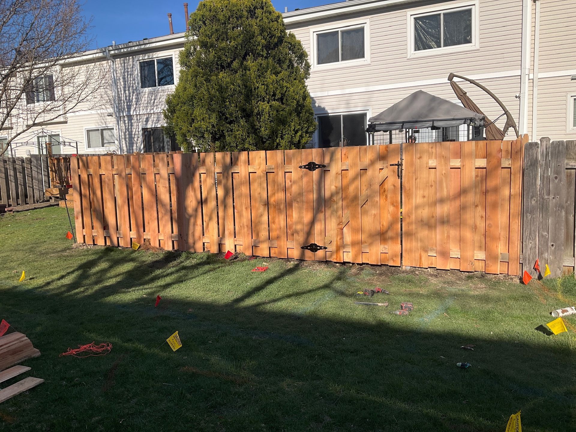 Wooden fence with gate in backyard; sunny day.
