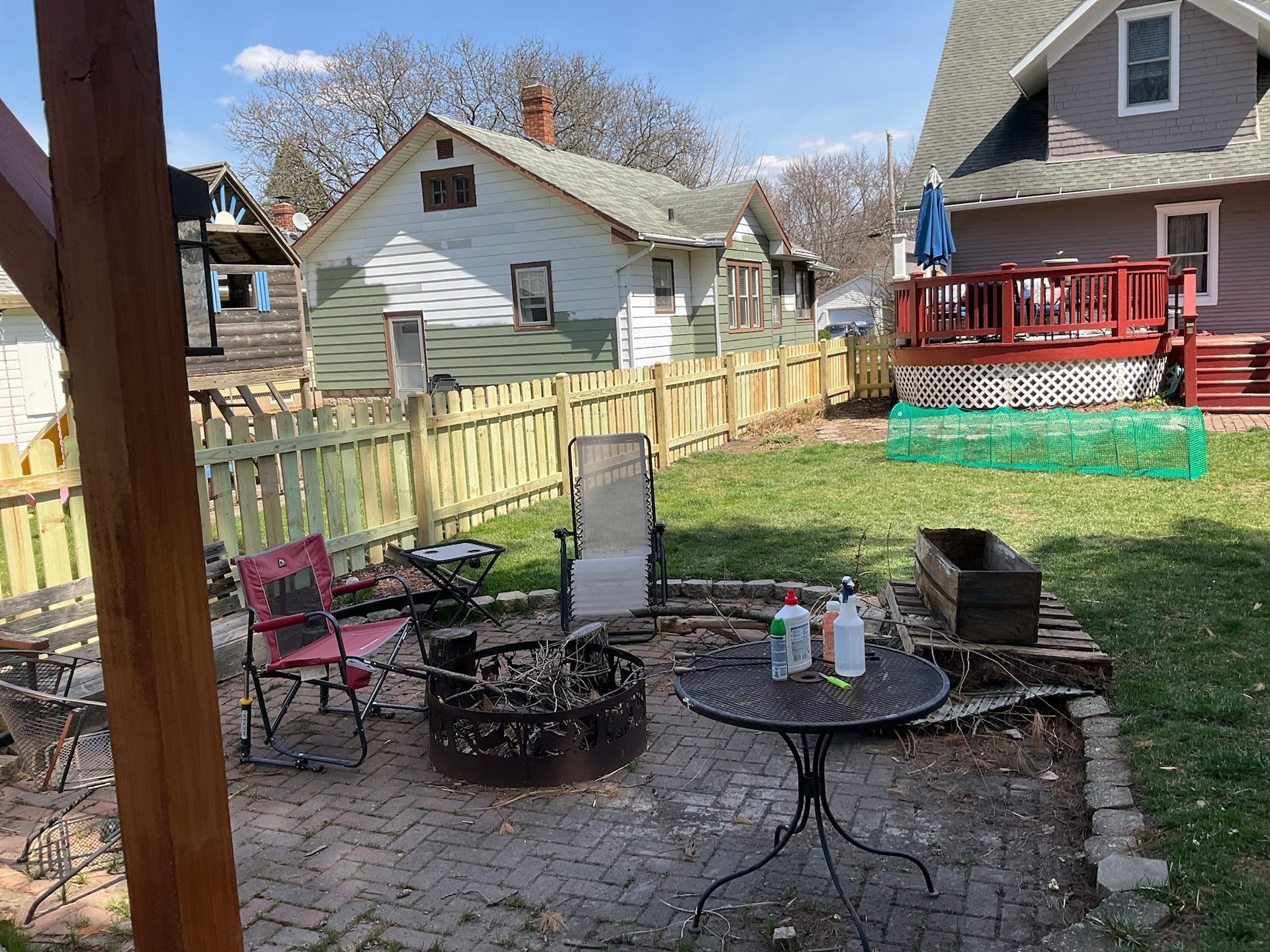 Backyard with a fire pit, patio furniture, and a wooden fence. Houses are in the background.