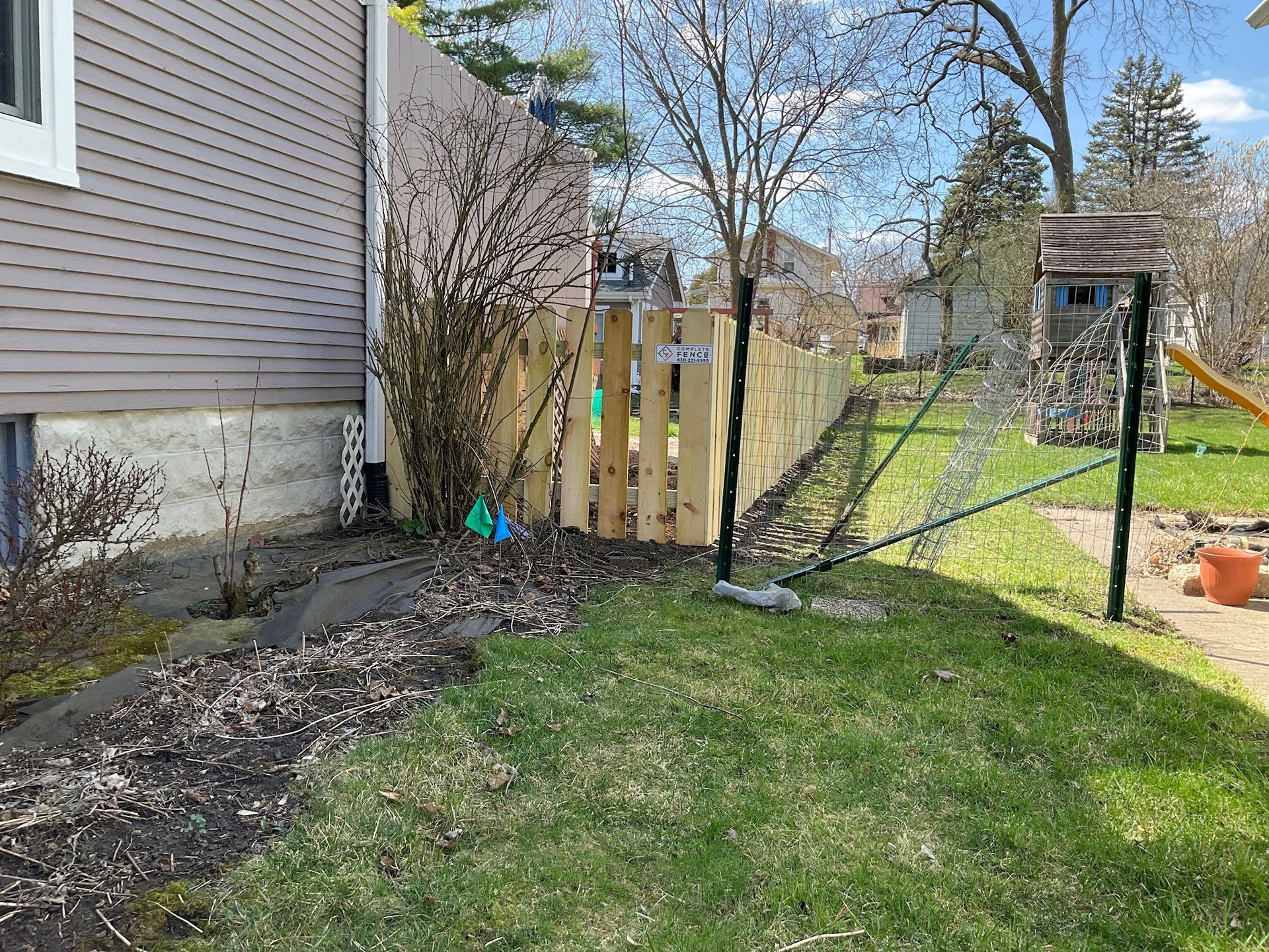 Wooden fence along a grassy backyard, next to a house.
