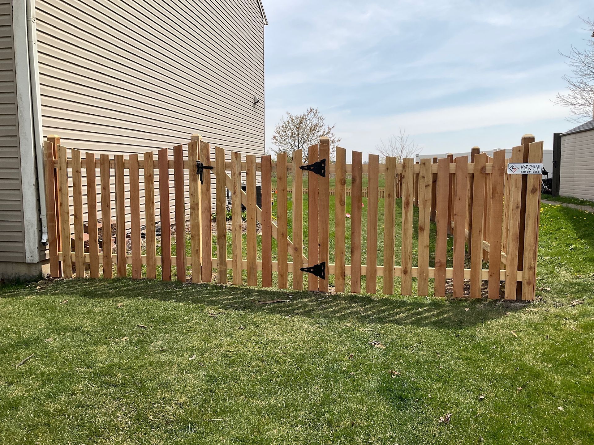 Wooden picket fence with a gate in a grassy yard.