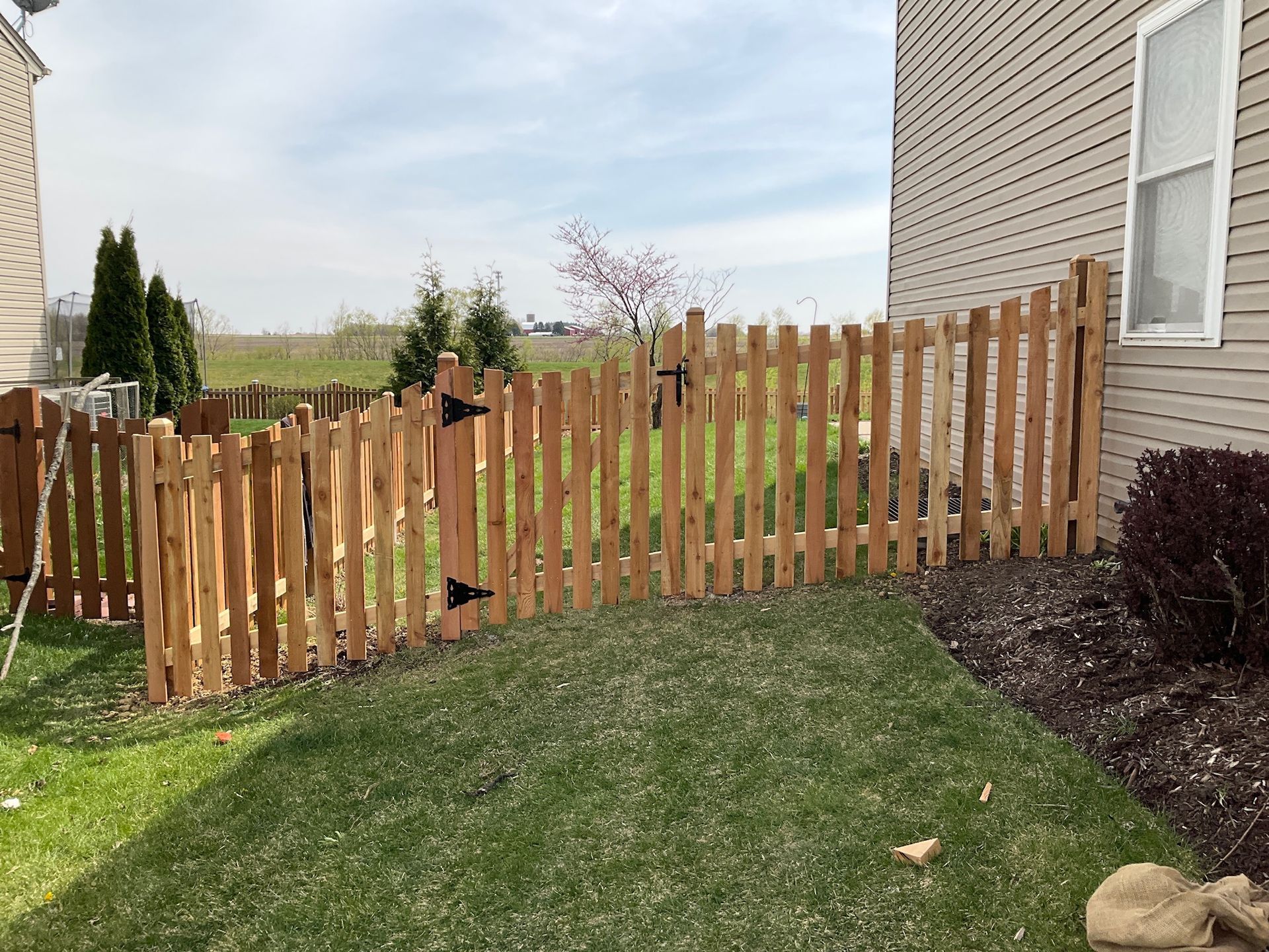 Wooden picket fence with two gates in backyard.