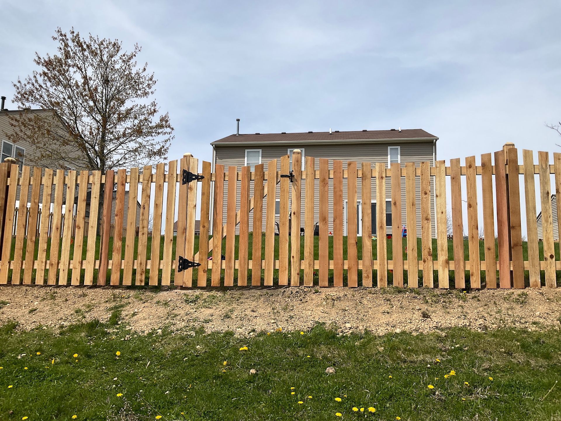 Wooden picket fence with gate in front of a house.