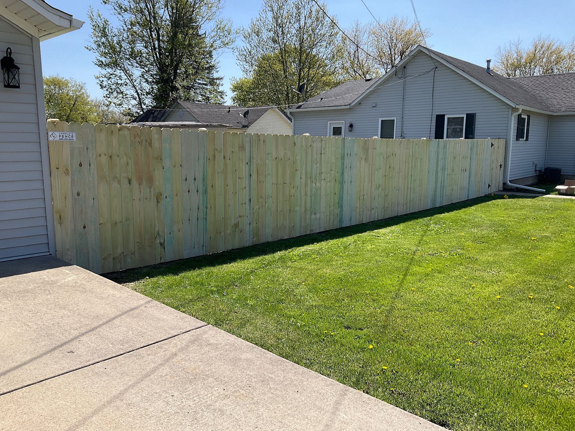 Wooden fence separating a green lawn from the house exterior.
