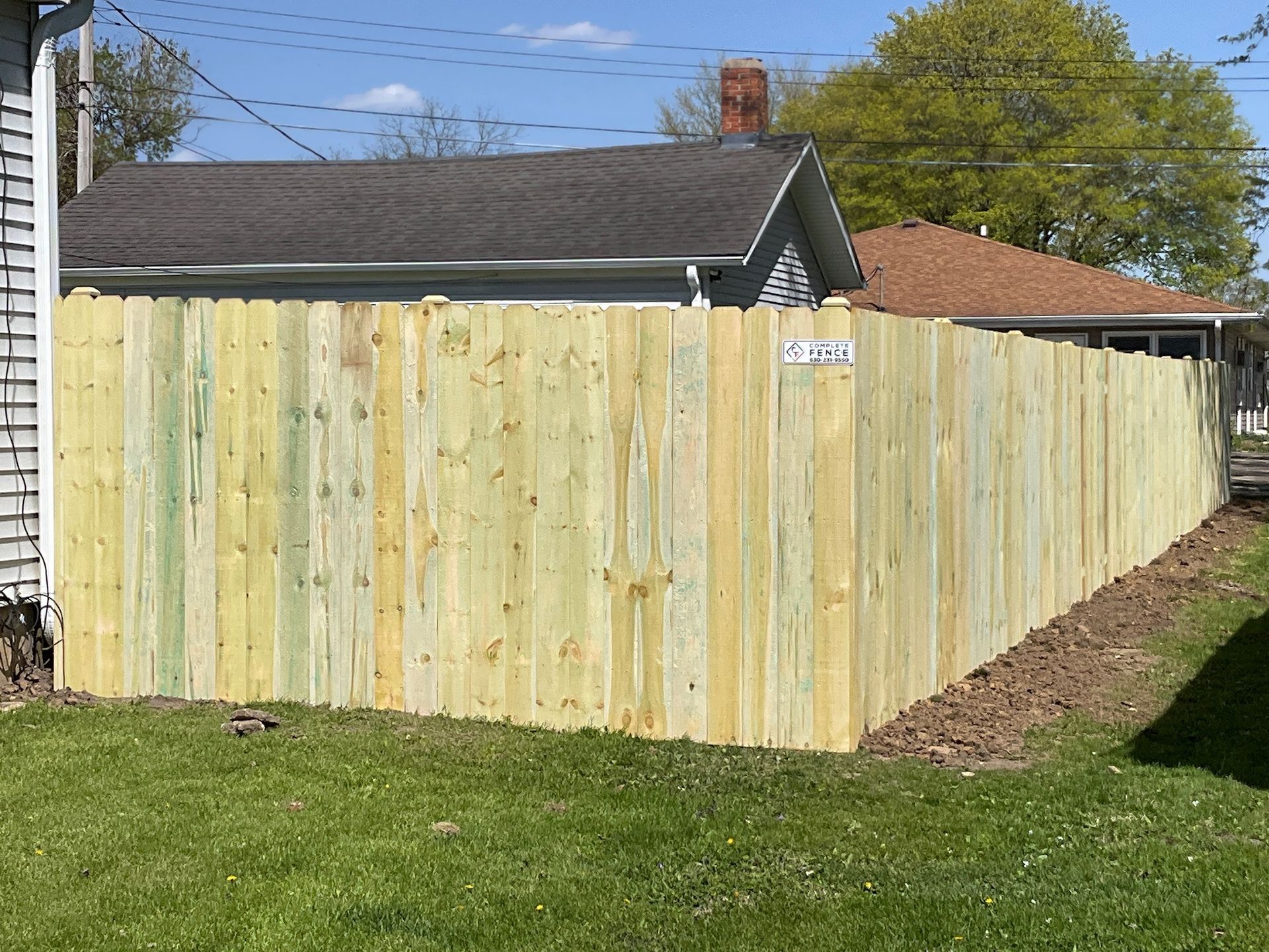 Wooden fence separating two residential properties on a sunny day.