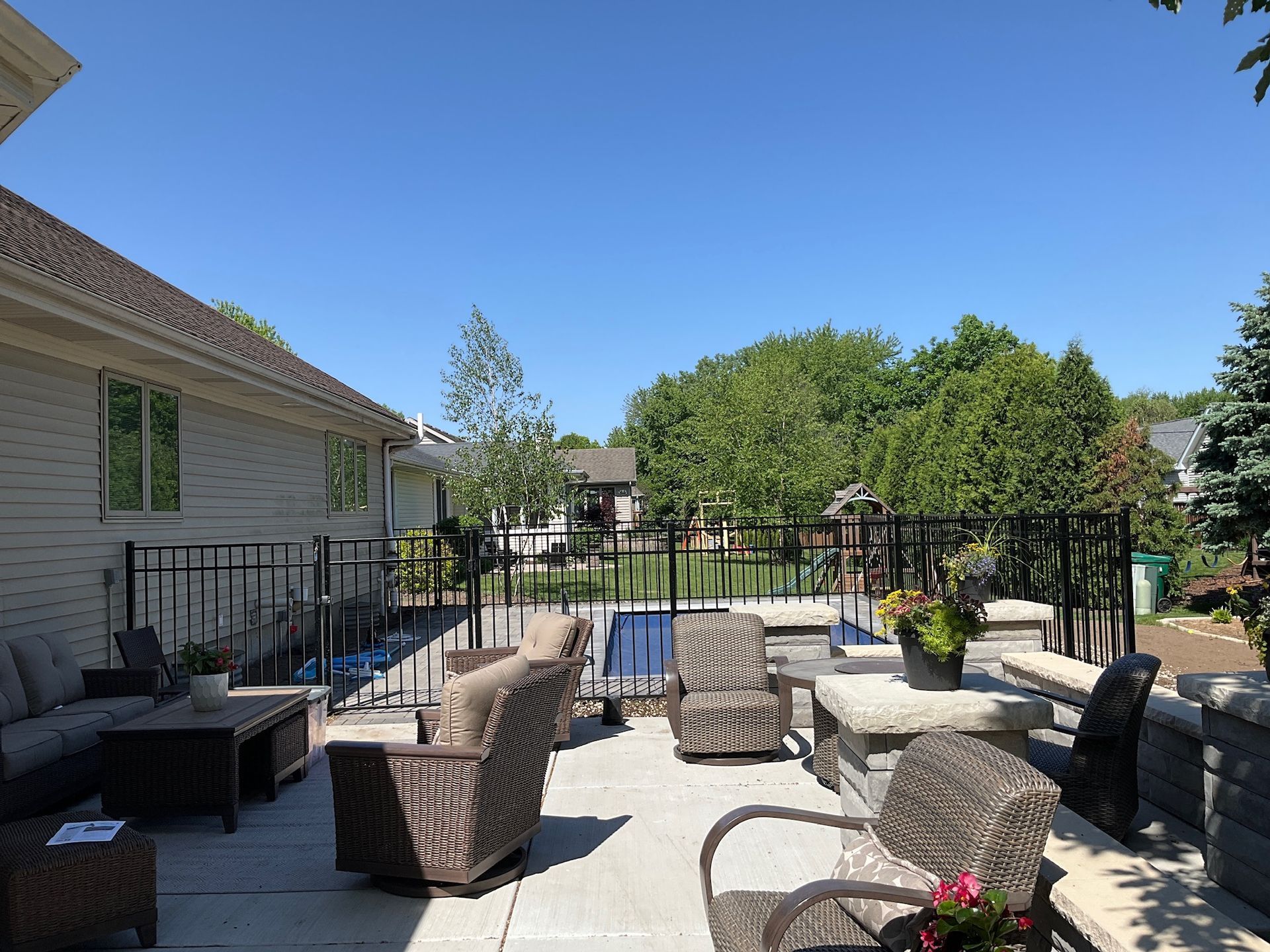Patio with outdoor seating and a pool, viewed on a sunny day.
