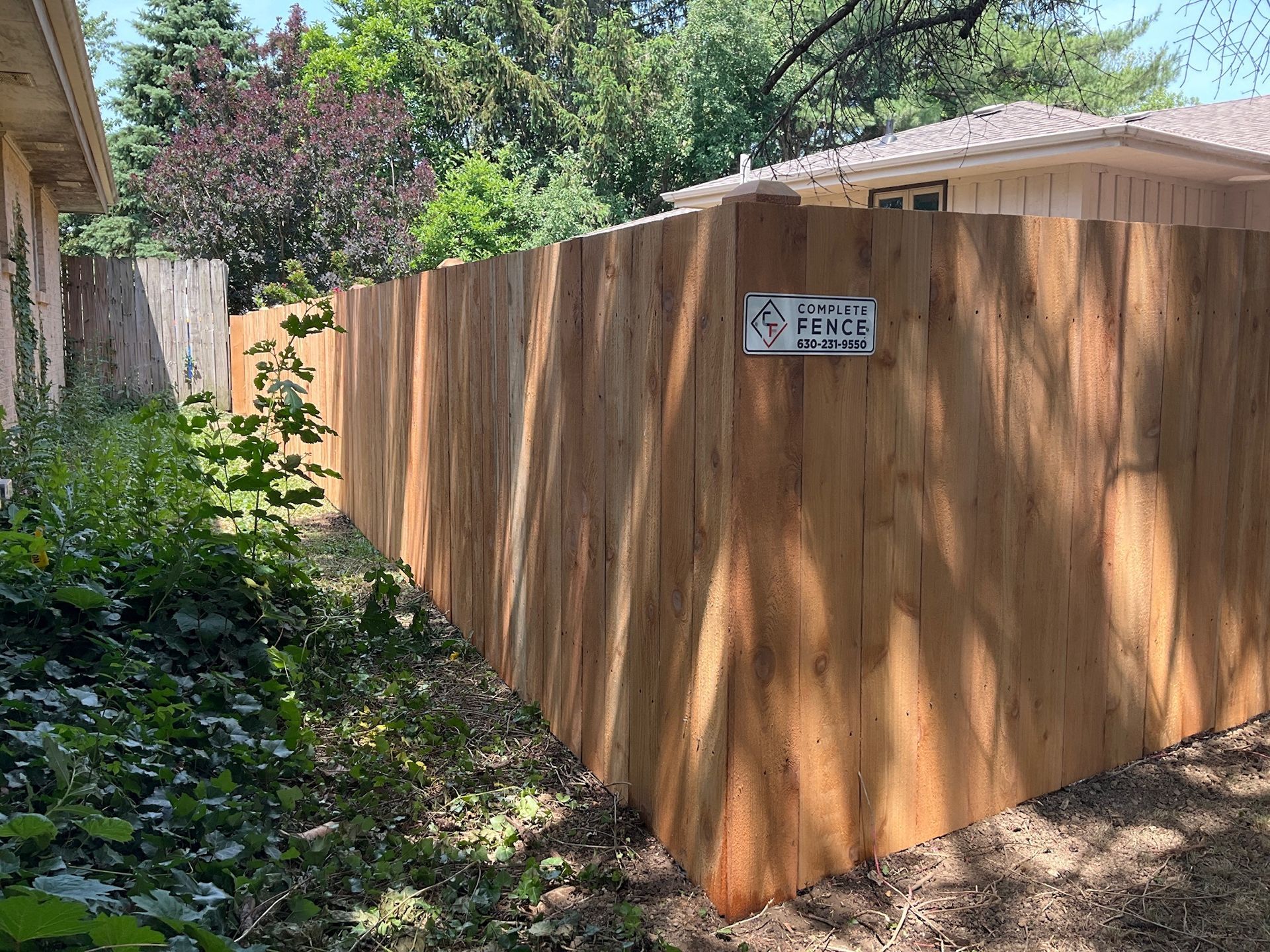Wooden fence in a yard with grass and trees.