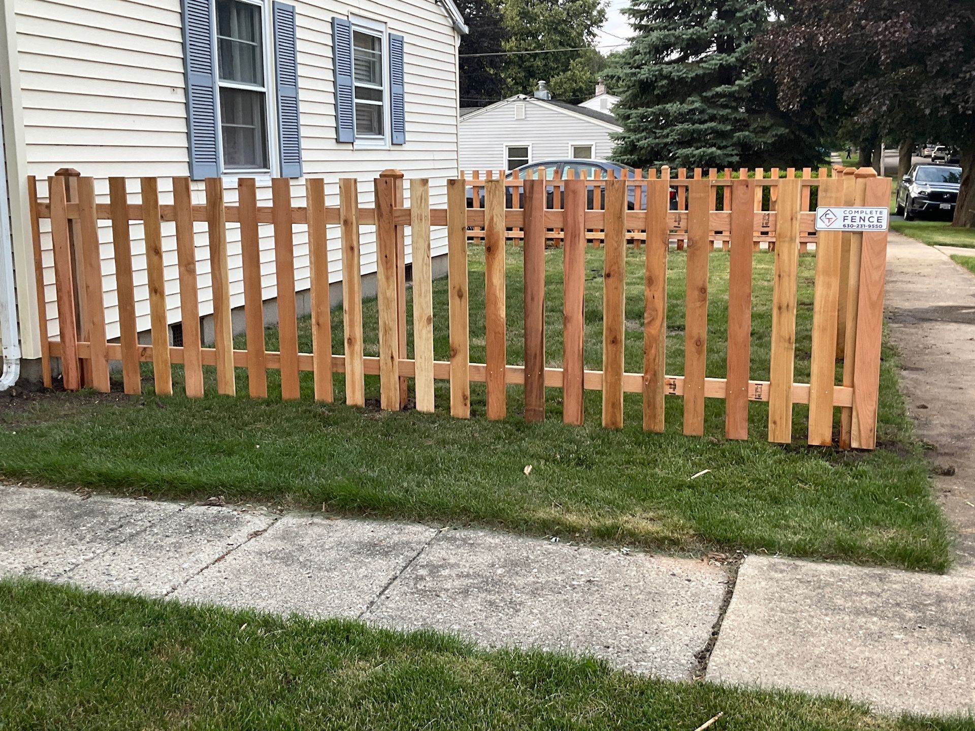 Wooden picket fence encloses a small yard in front of a house.