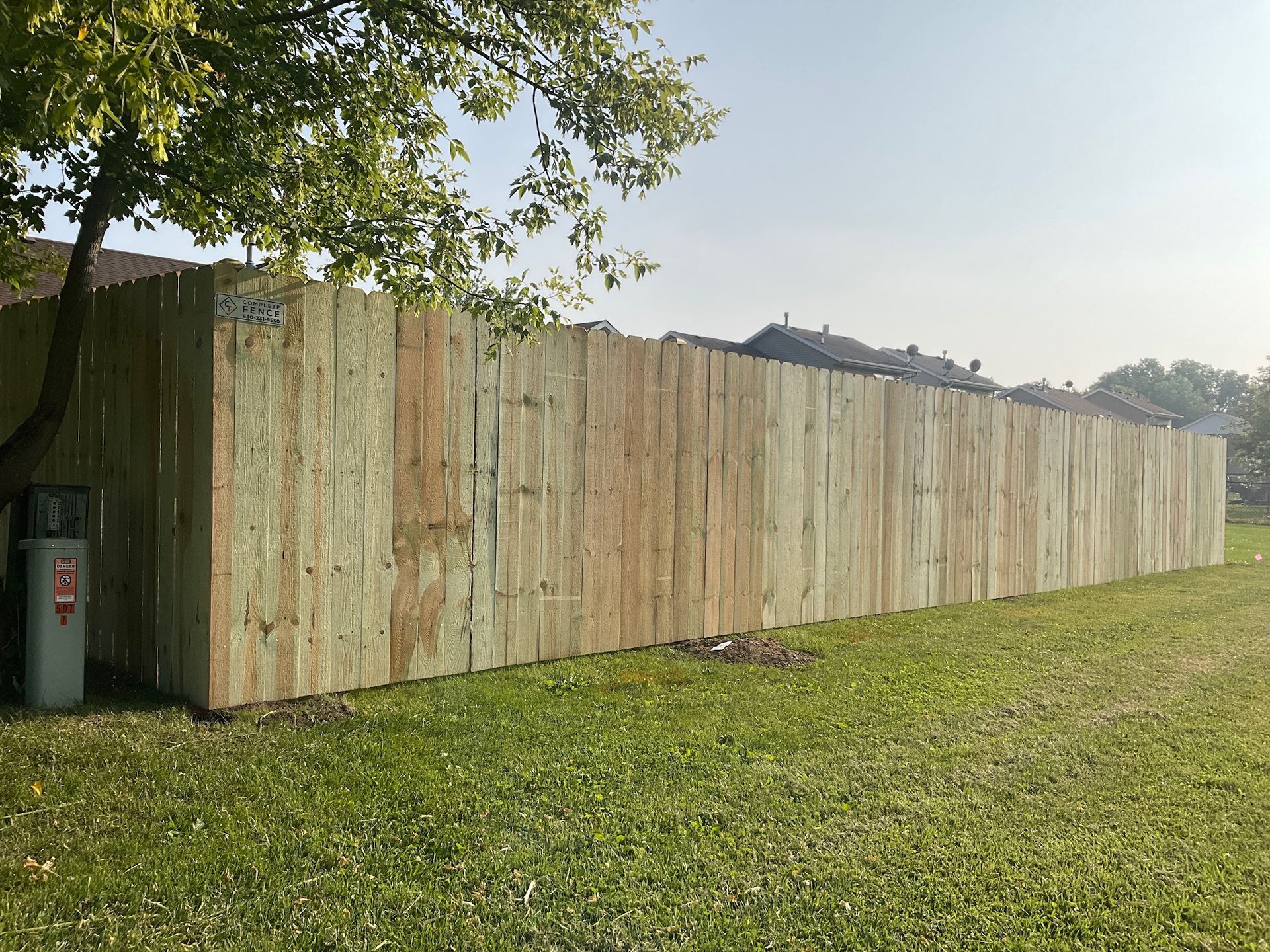 Long, weathered, concrete wall in a grassy park, a tree at the left.
