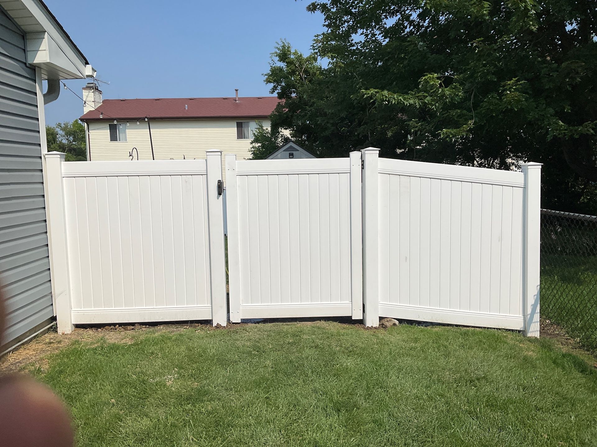 White vinyl fence with gate in a grassy backyard.