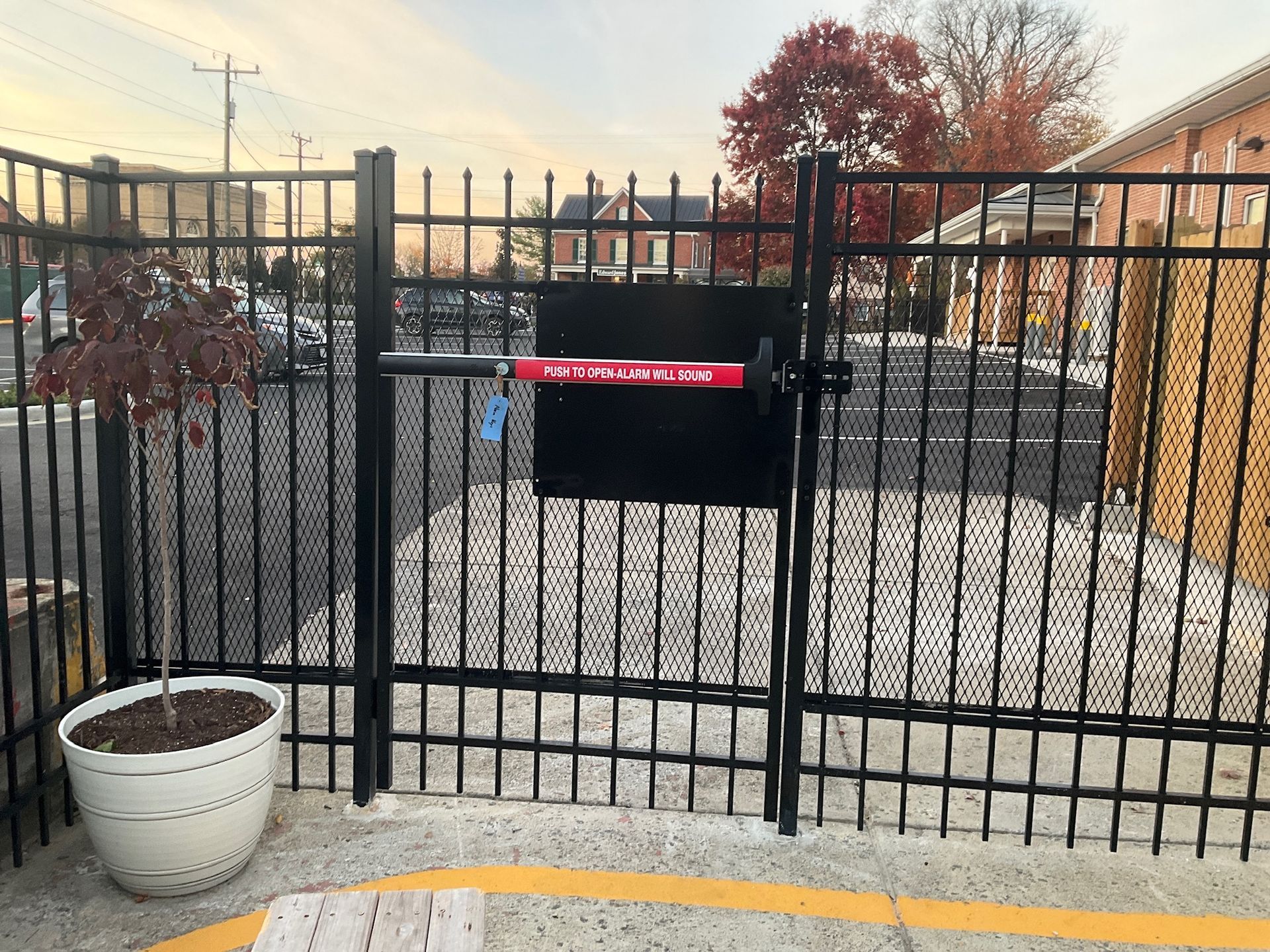 Black metal security gate with red exit bar.