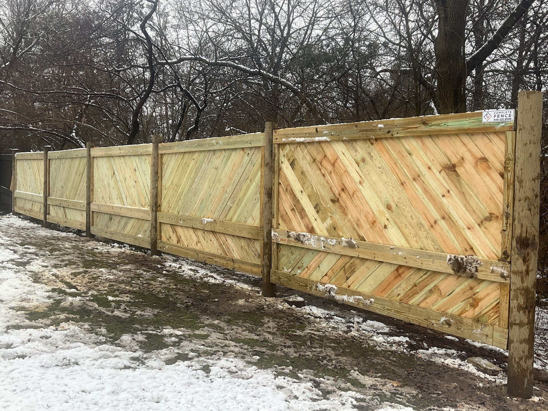 Wooden fence with diagonal planks in a snowy outdoor setting.