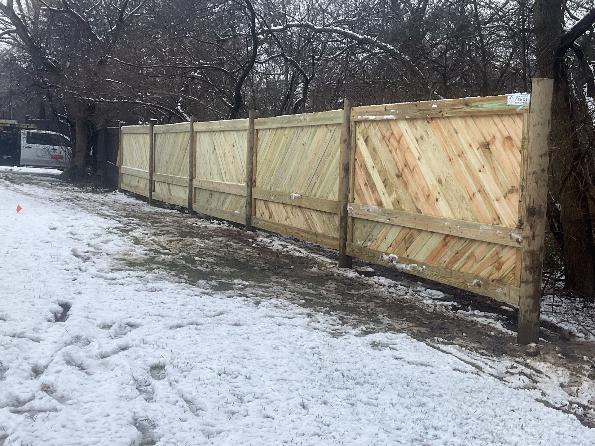 Wooden fence with diagonal planks in a snowy outdoor setting.