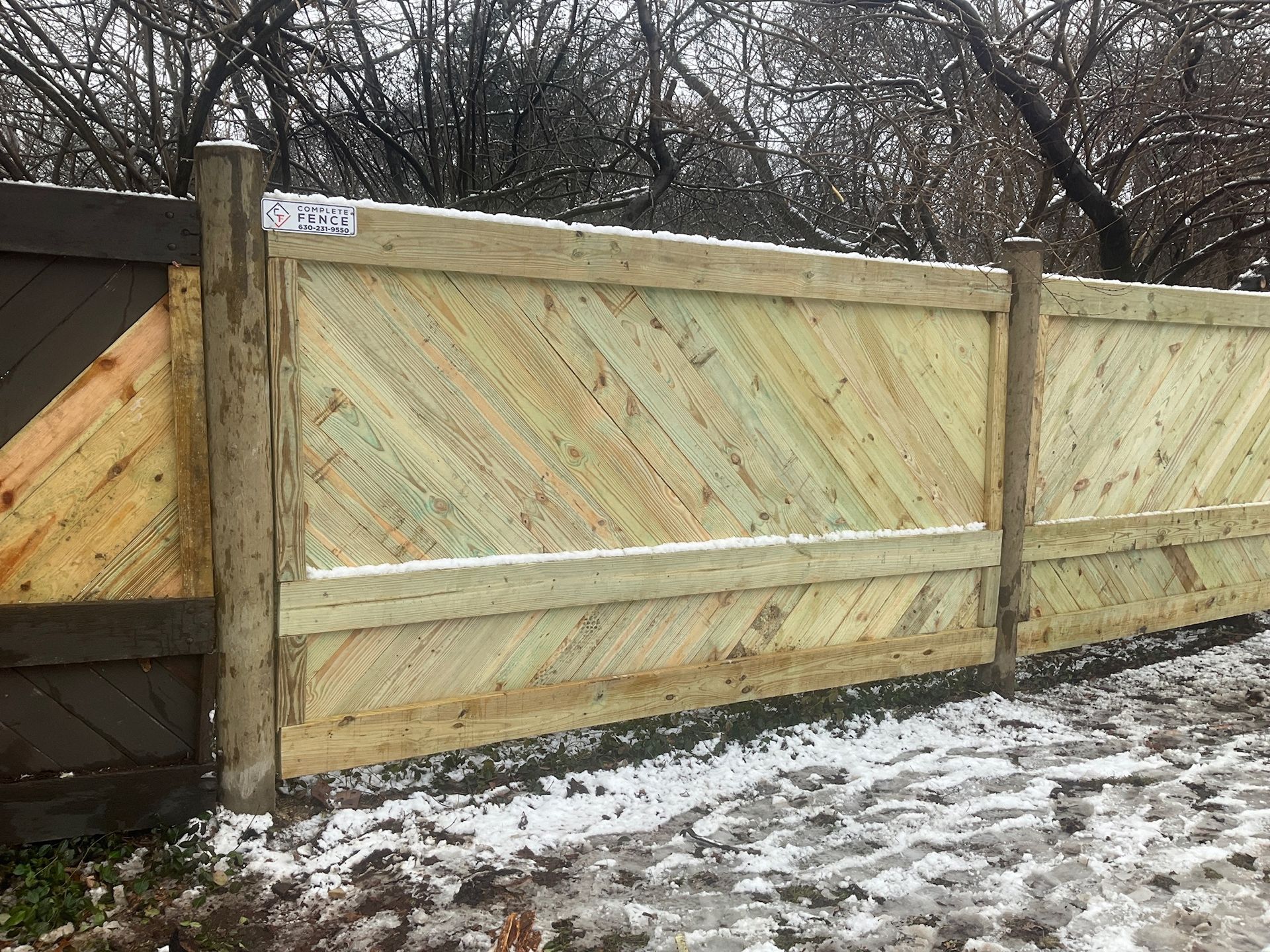 Wooden fence with diagonal planks in a snowy environment.