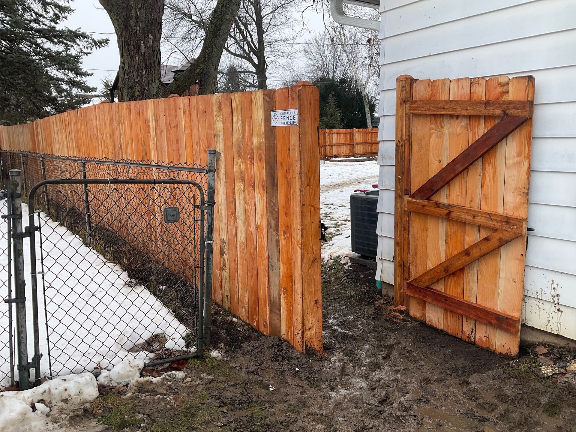 Wooden fence with an open gate; snow on the ground.