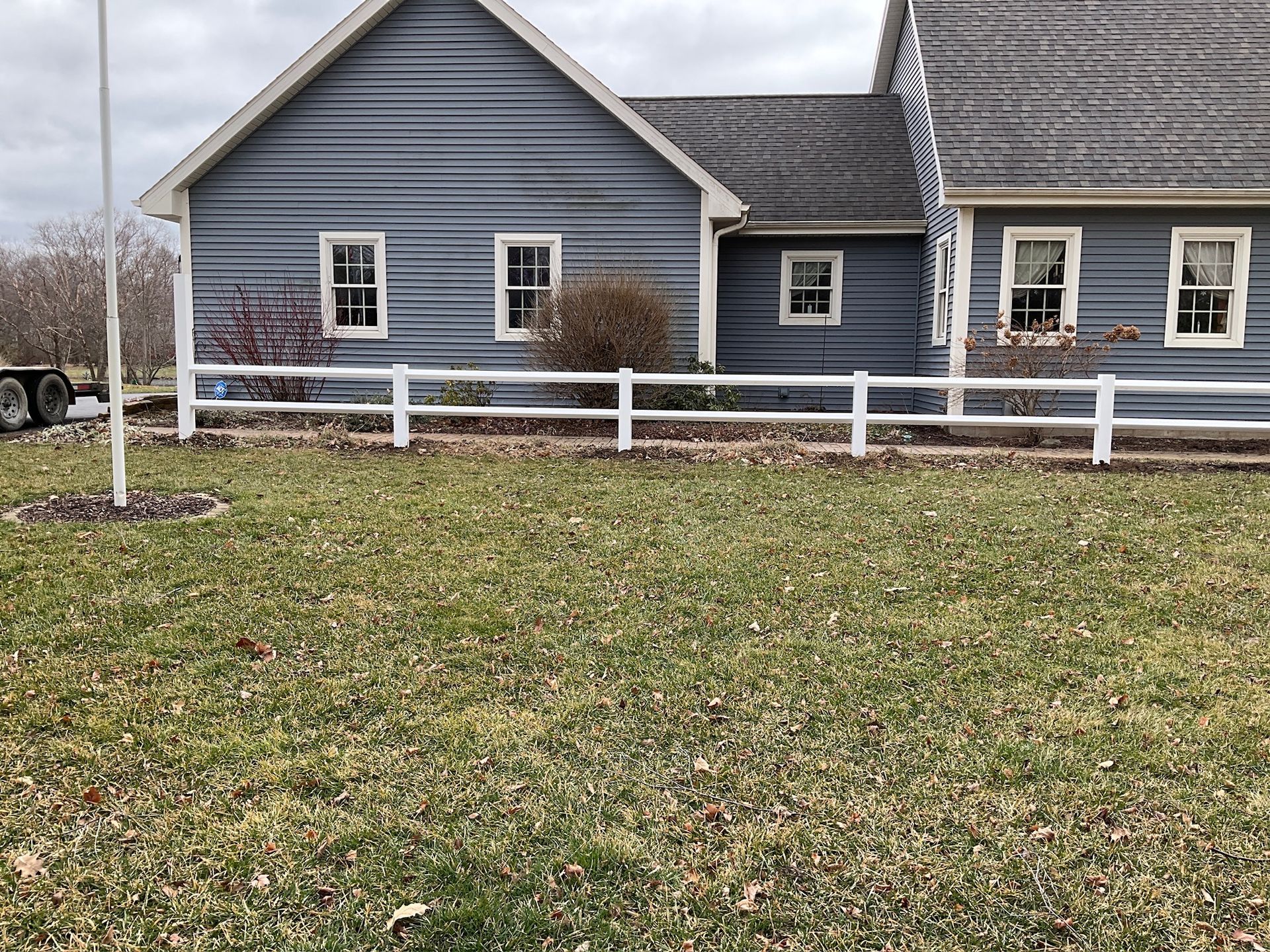 Blue house with white fence and overcast sky.