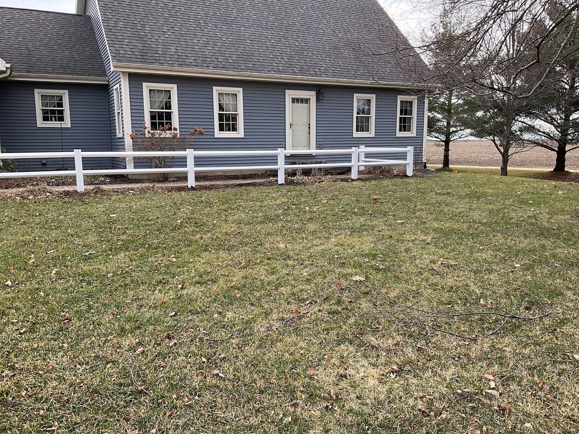 Blue house with white picket fence and brown grass.