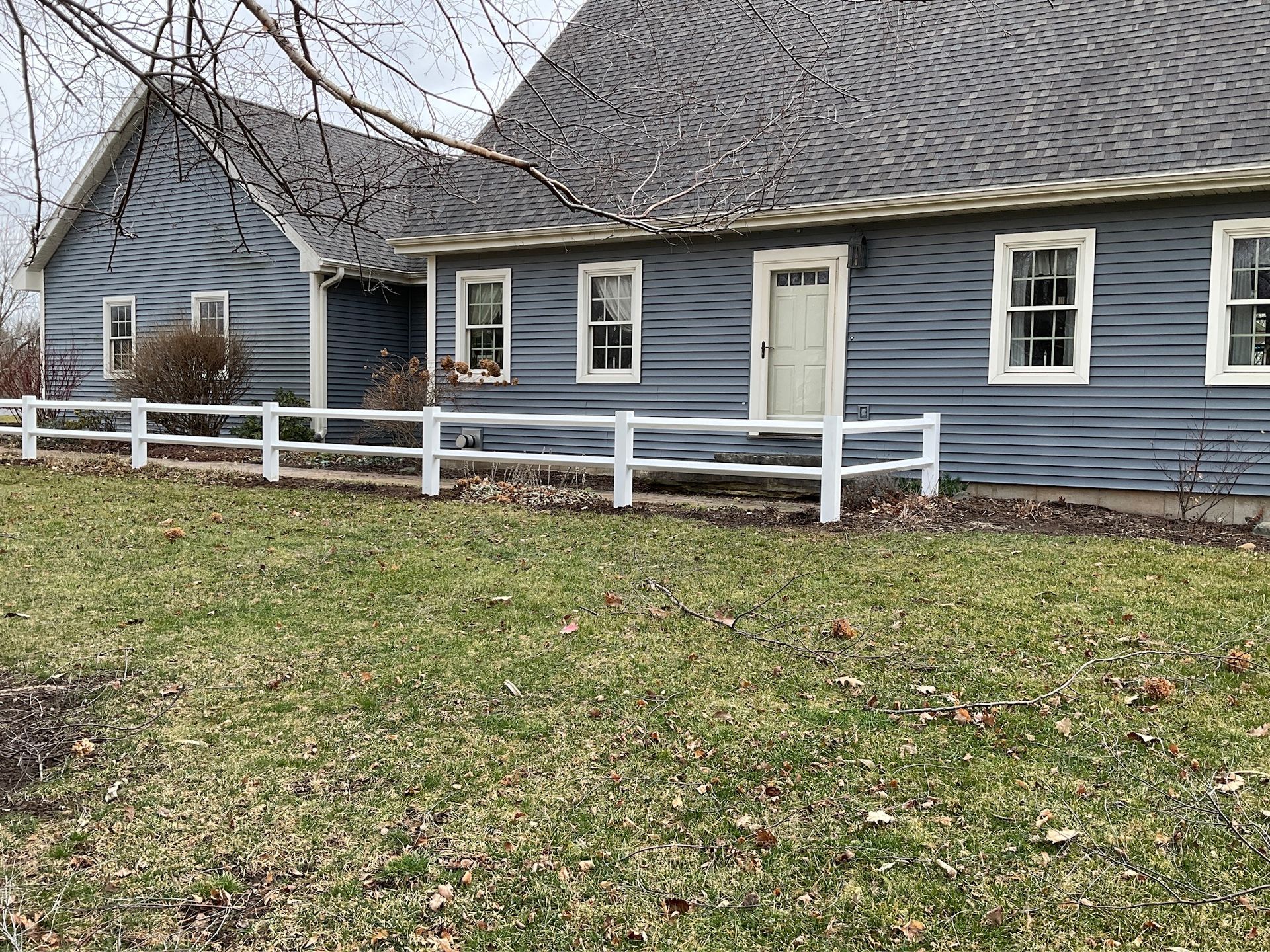 Blue house with white fence and grass lawn.
