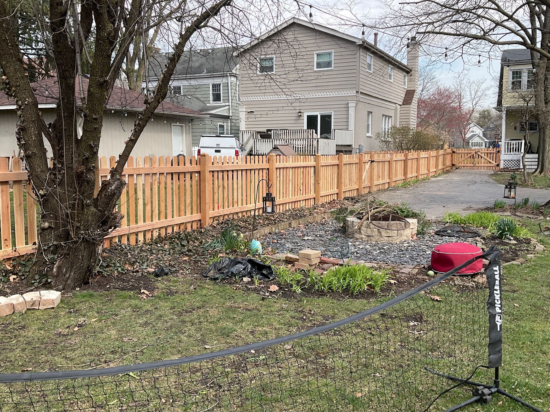 Wooden fence in a backyard; a two-story house is visible in the background.