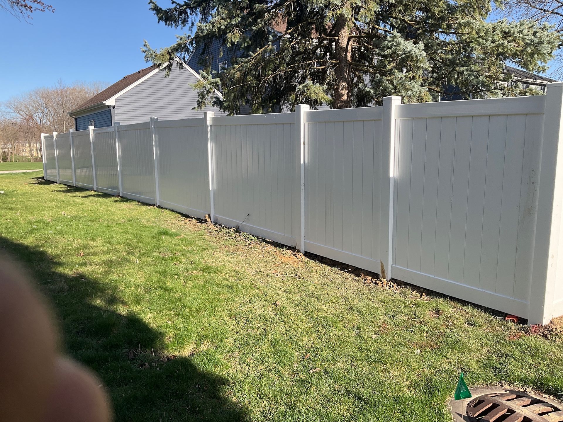 White vinyl fence along grassy yard, sunny day.