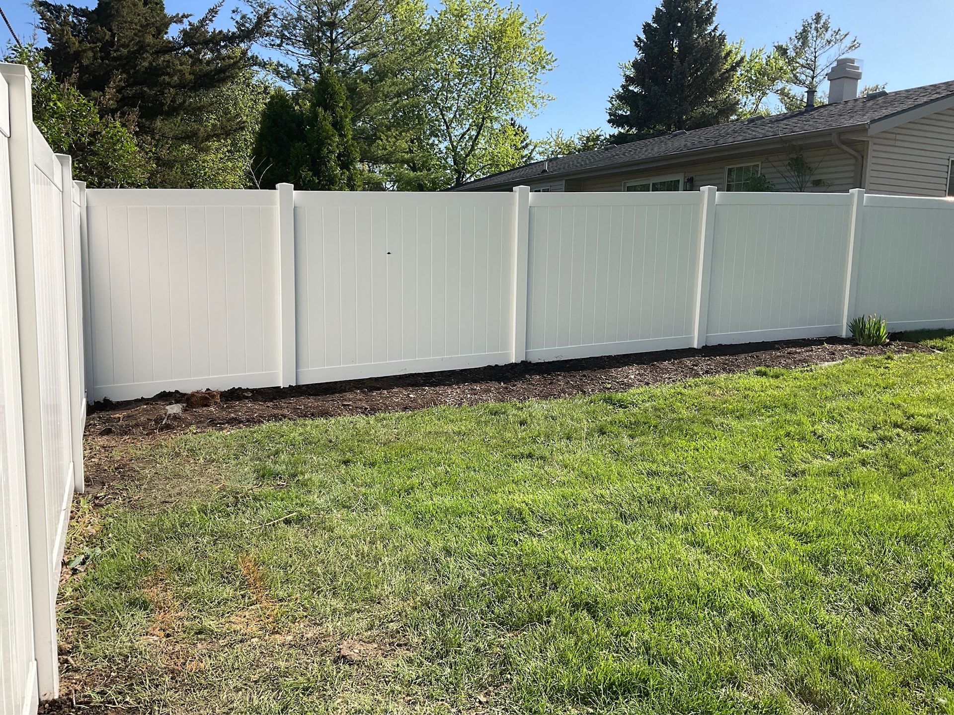 White vinyl fence bordering a grassy backyard.