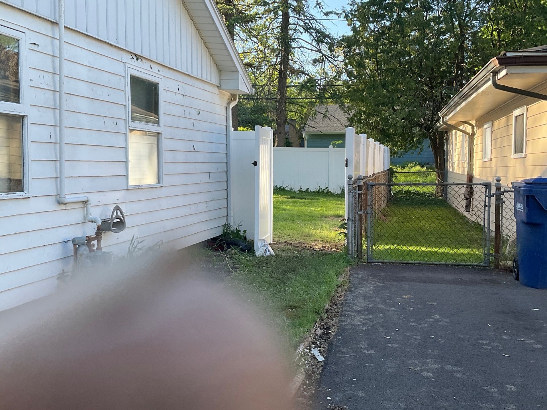 View of white buildings and a fence along a grassy area and driveway.