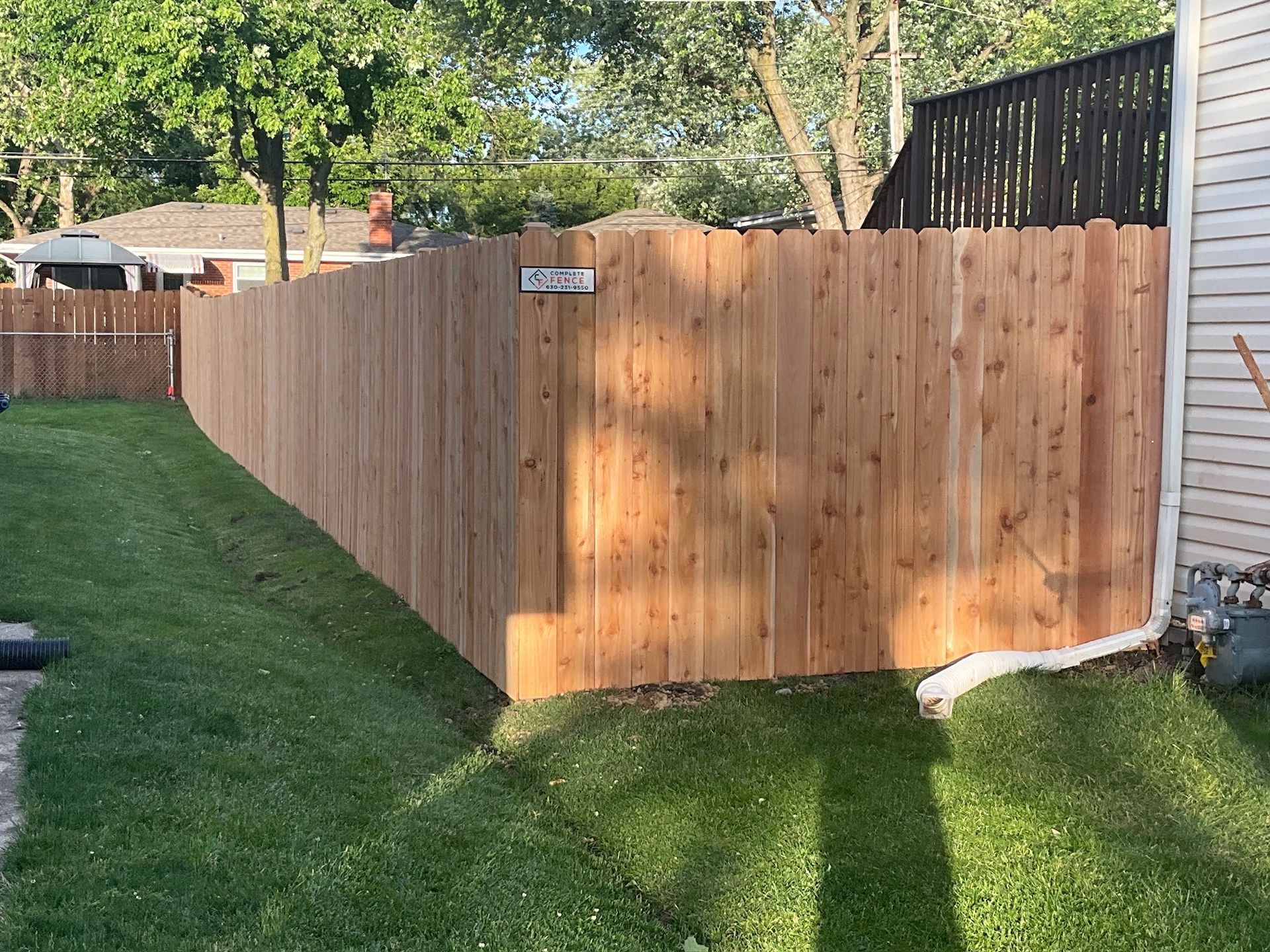 Wooden privacy fence in a backyard with green grass and a house.