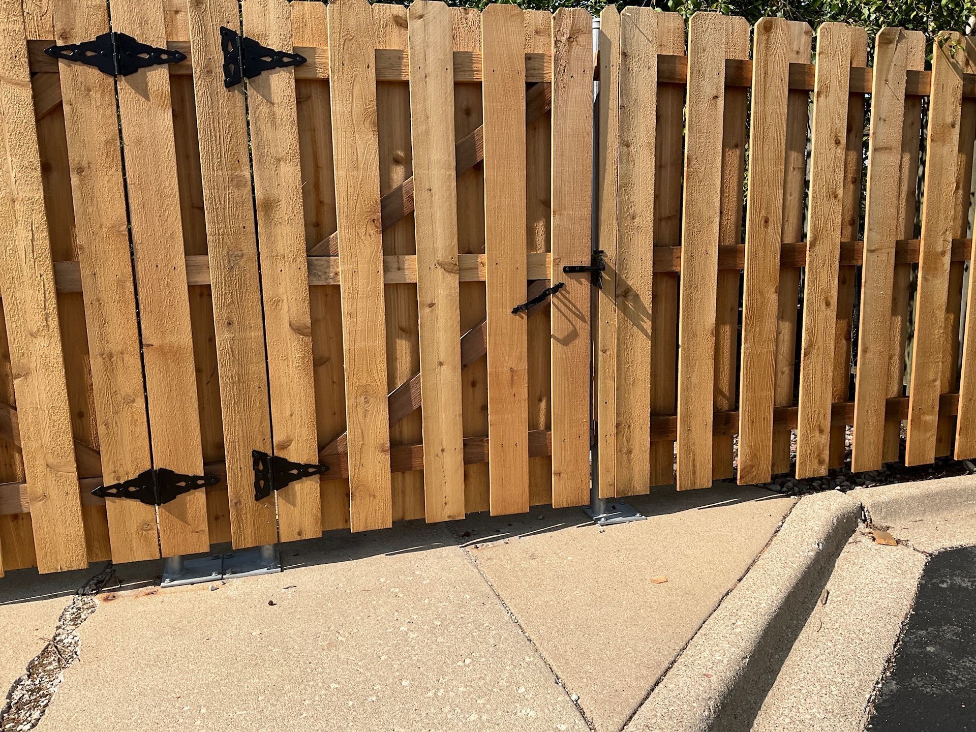 Wooden fence with a gate, black hinges and latch.