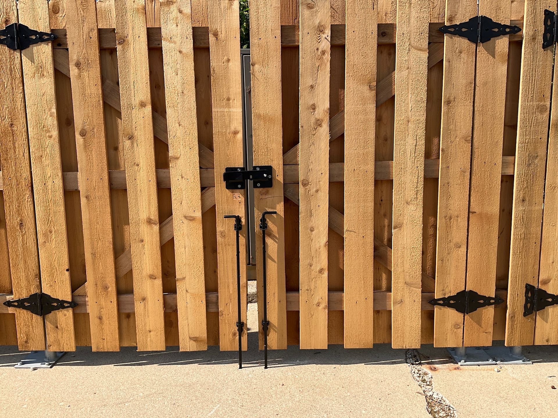 Wooden gate with black hinges and latch, closed.