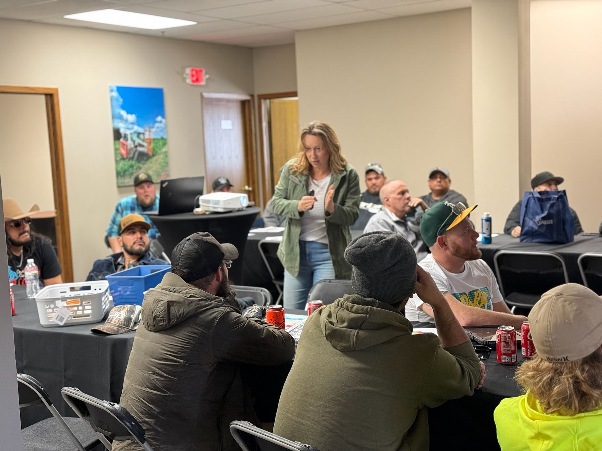 A woman presents to a seated group. They are in a conference room with a projector.