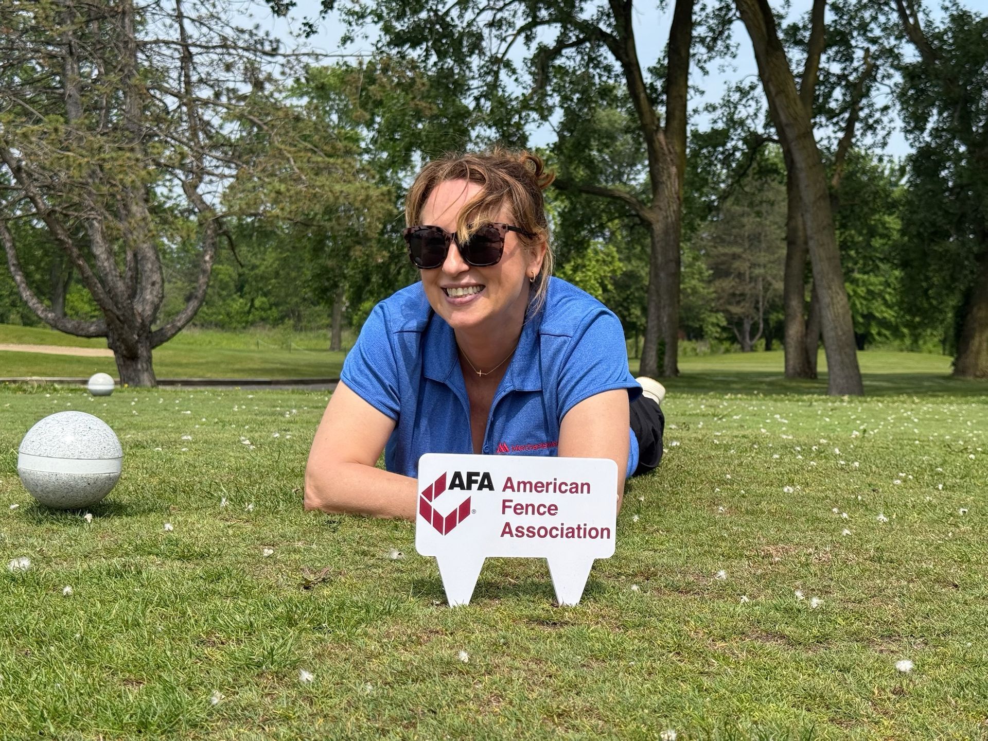 Woman in sunglasses smiling, lying on grass with 