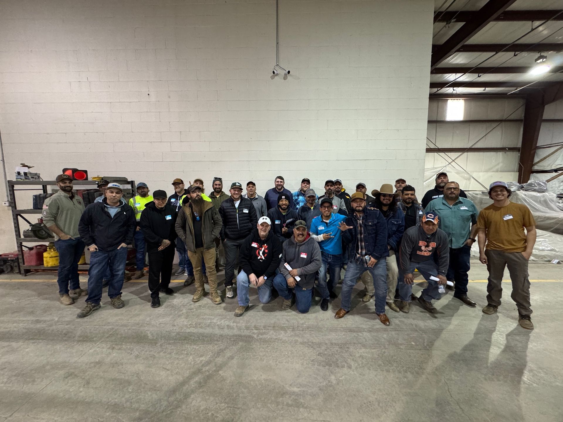 Group of men posing indoors. They are likely workers in a warehouse or workshop.