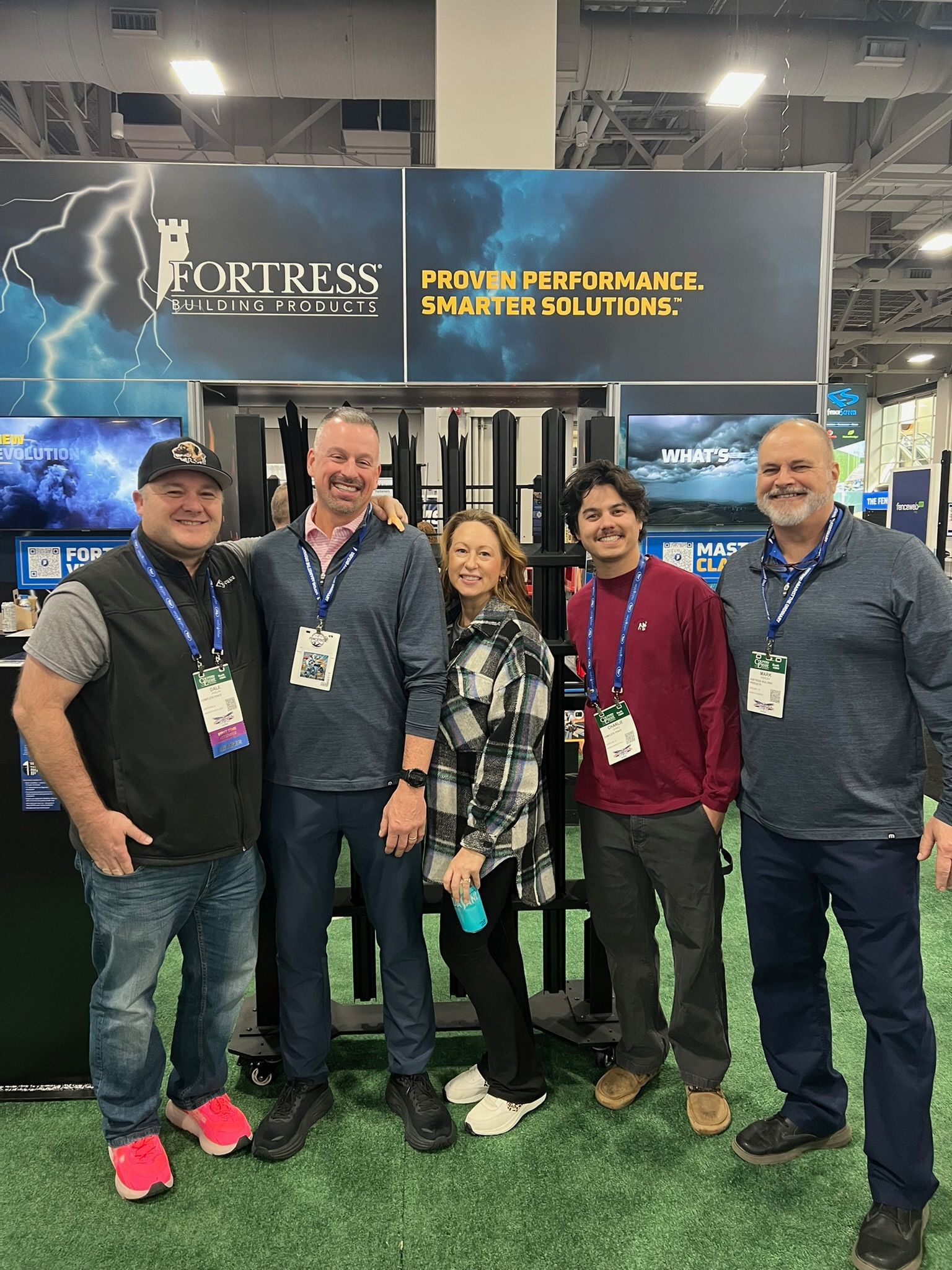 Five people pose in front of a Fortress Acoustics booth at a trade show.