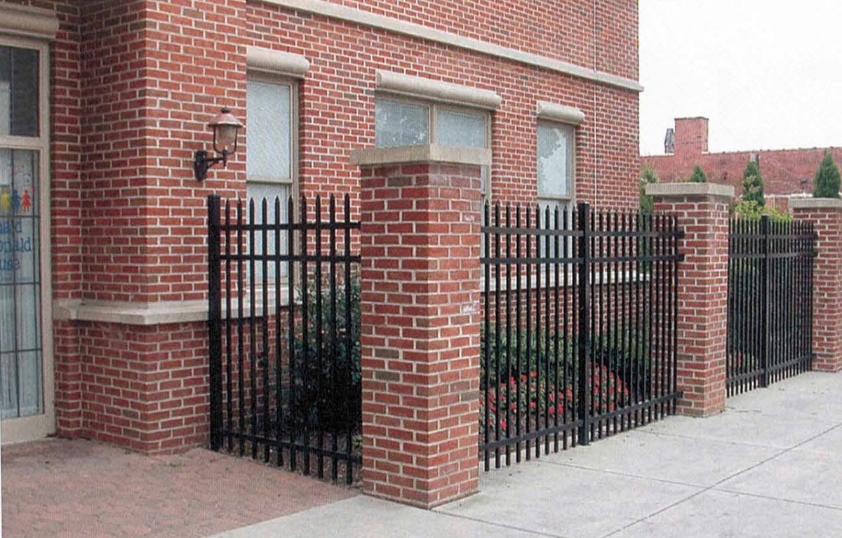 Brick building with black metal fence and brick pillars.