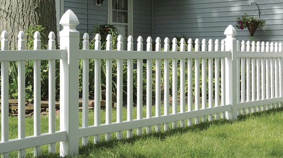 White picket fence on green lawn, in front of a house.