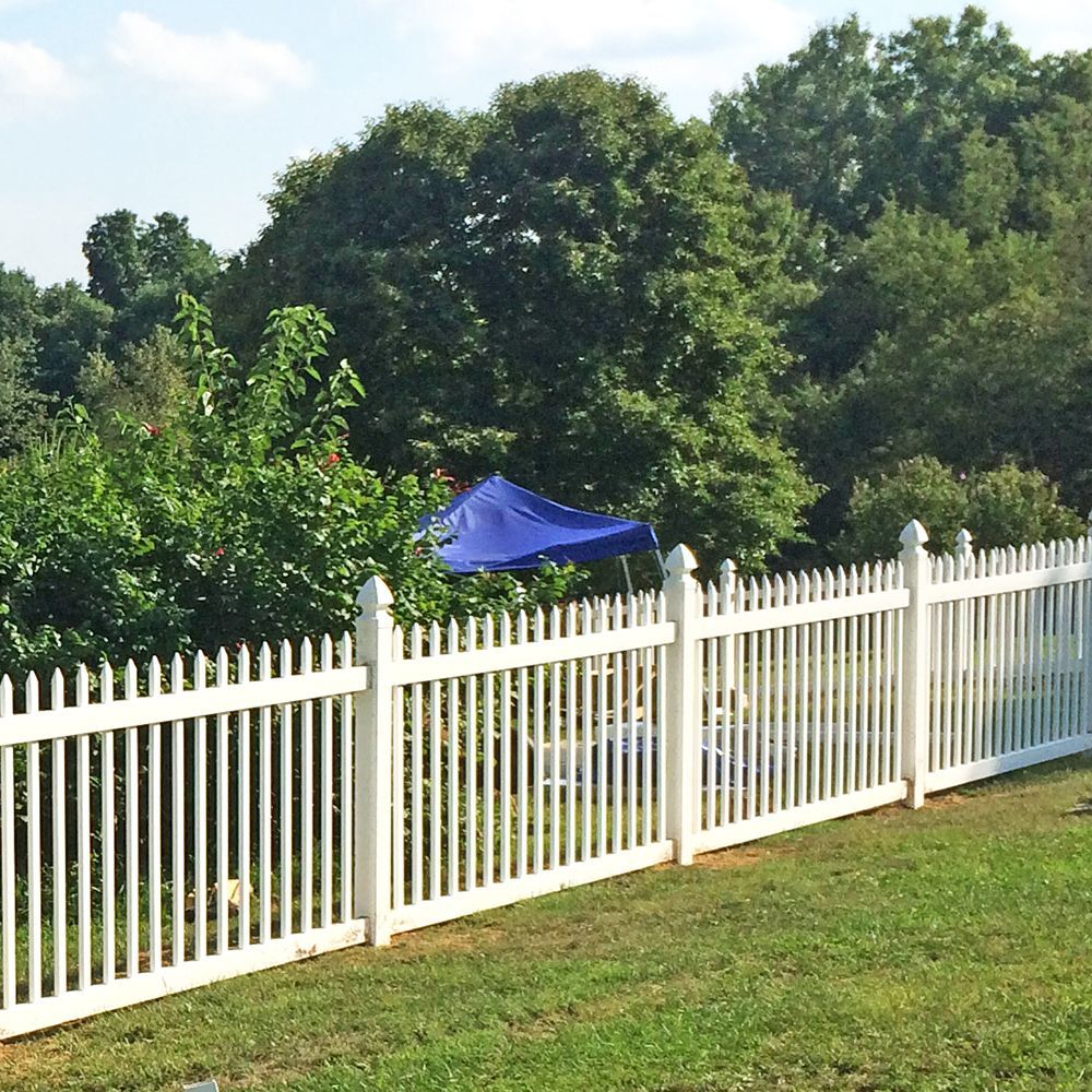 White picket fence in a grassy yard, trees in the background, blue tent visible.