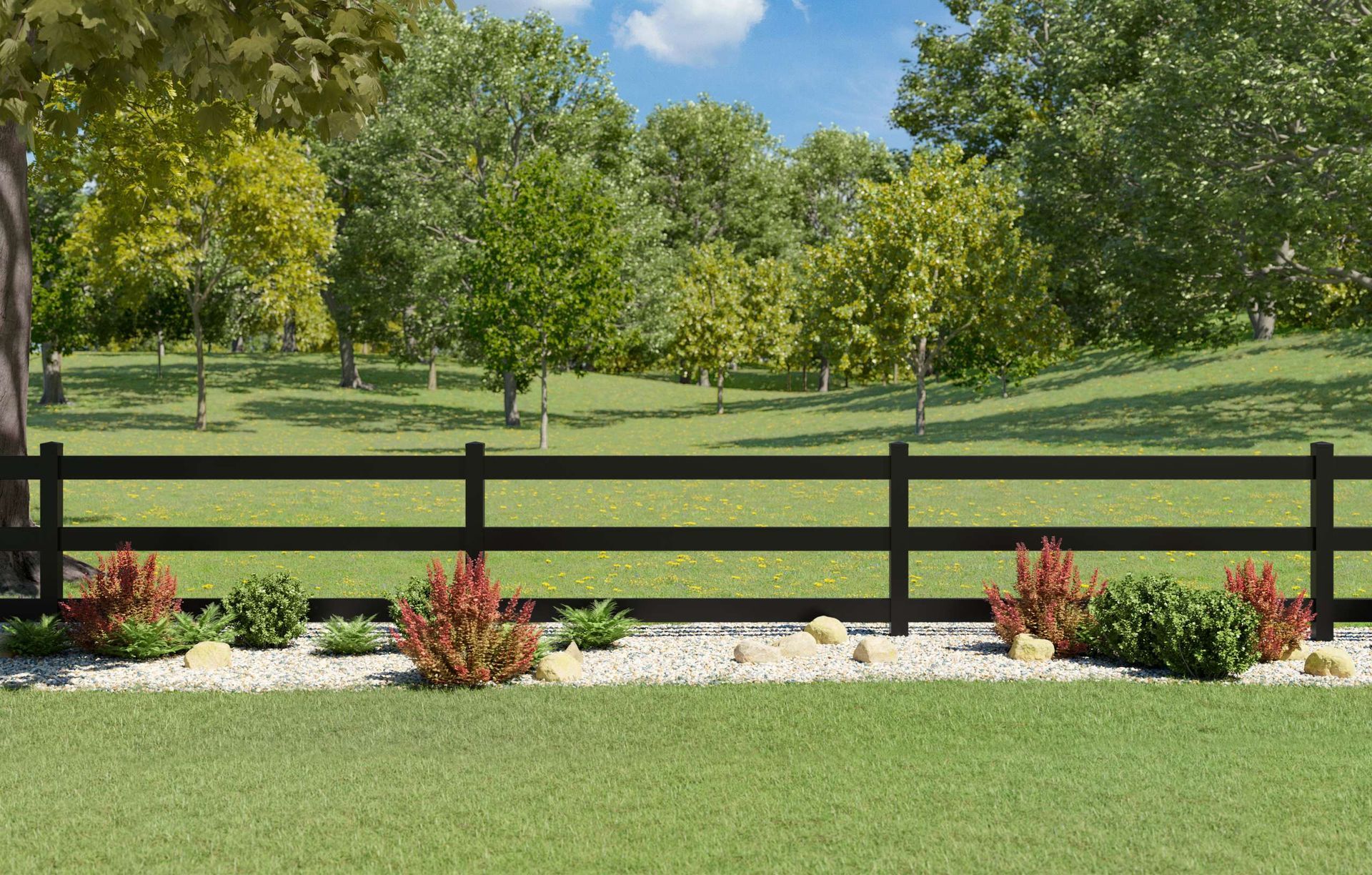 Black fence with red bushes and stones in front of a green yard, trees in the background under a blue sky.