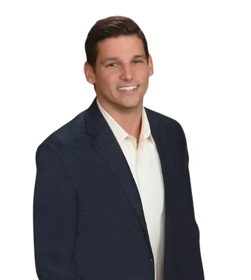 Man in blue blazer and white shirt smiles at the camera.