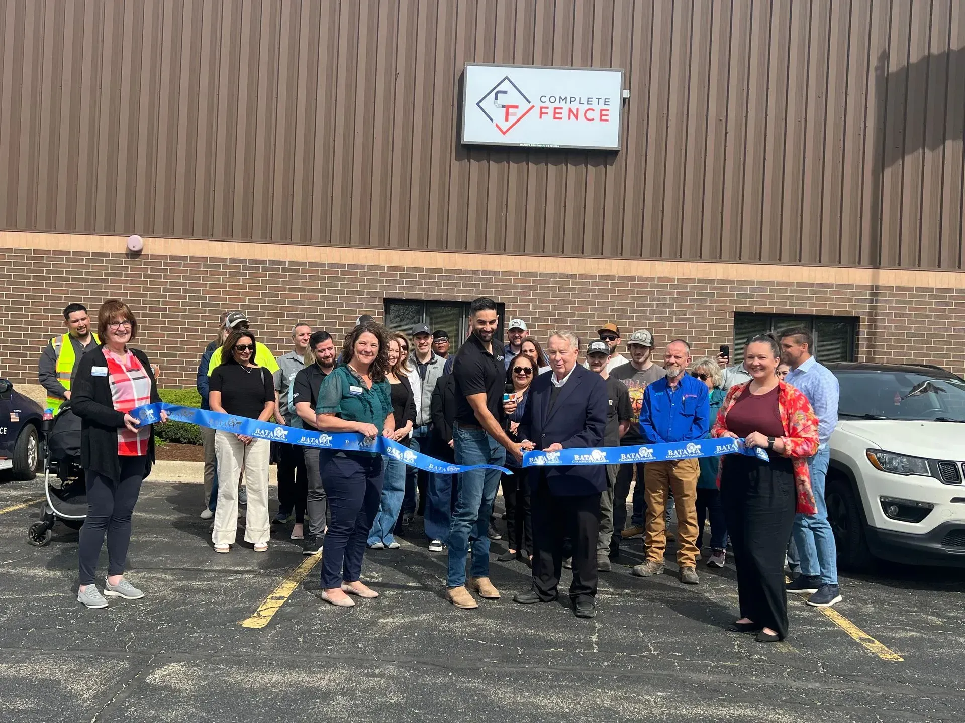 People at a ribbon-cutting ceremony in front of a building with a 