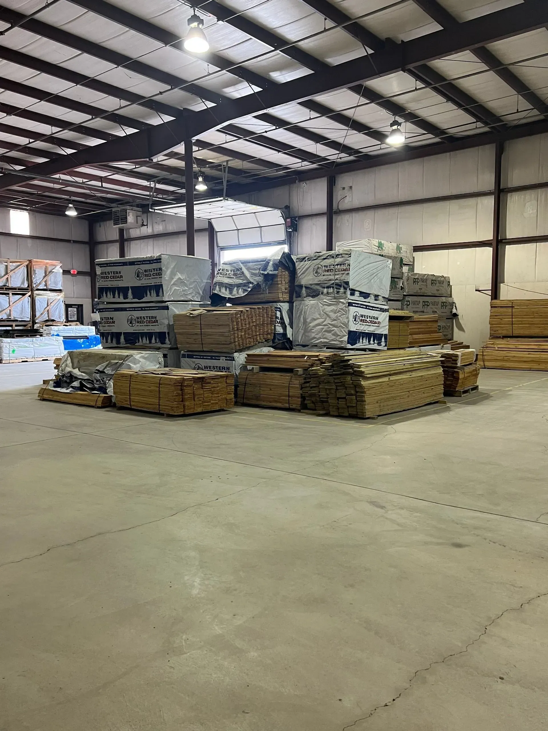Warehouse interior with stacks of lumber and building materials.