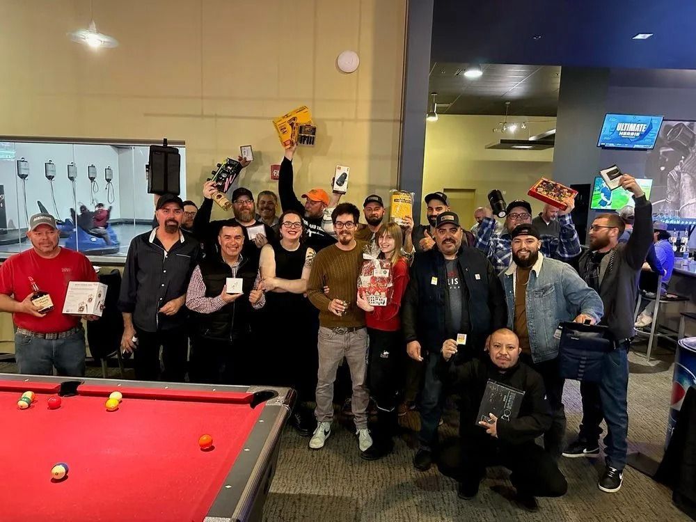 Group of people celebrating by a pool table, holding items, in a bar setting.
