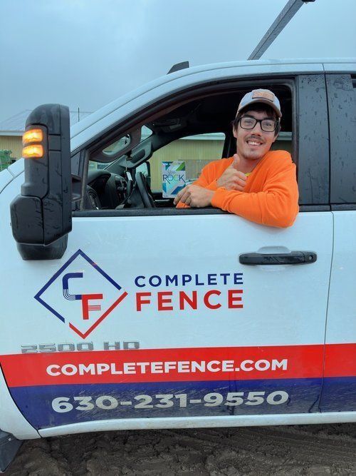 Man in orange shirt in truck giving thumbs-up; truck has 