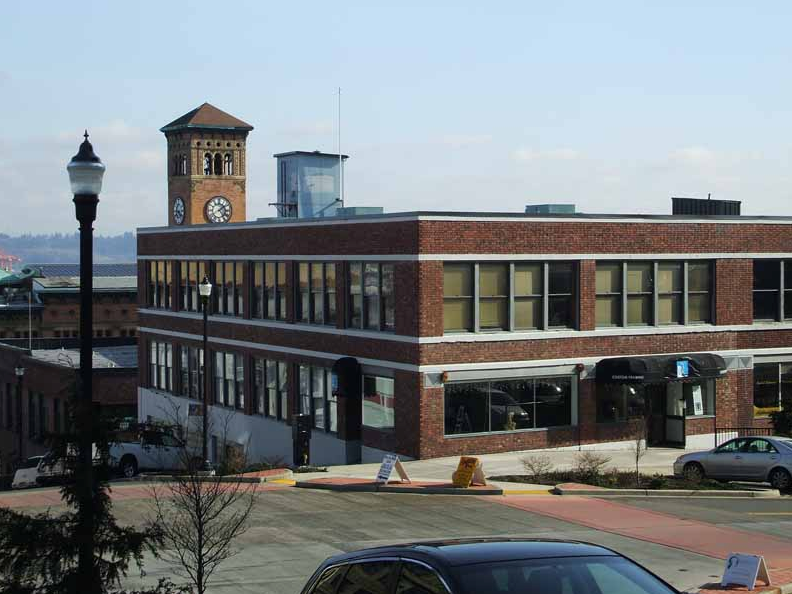 Brick building with clock tower, water tower, and street lamp on a sunny day.