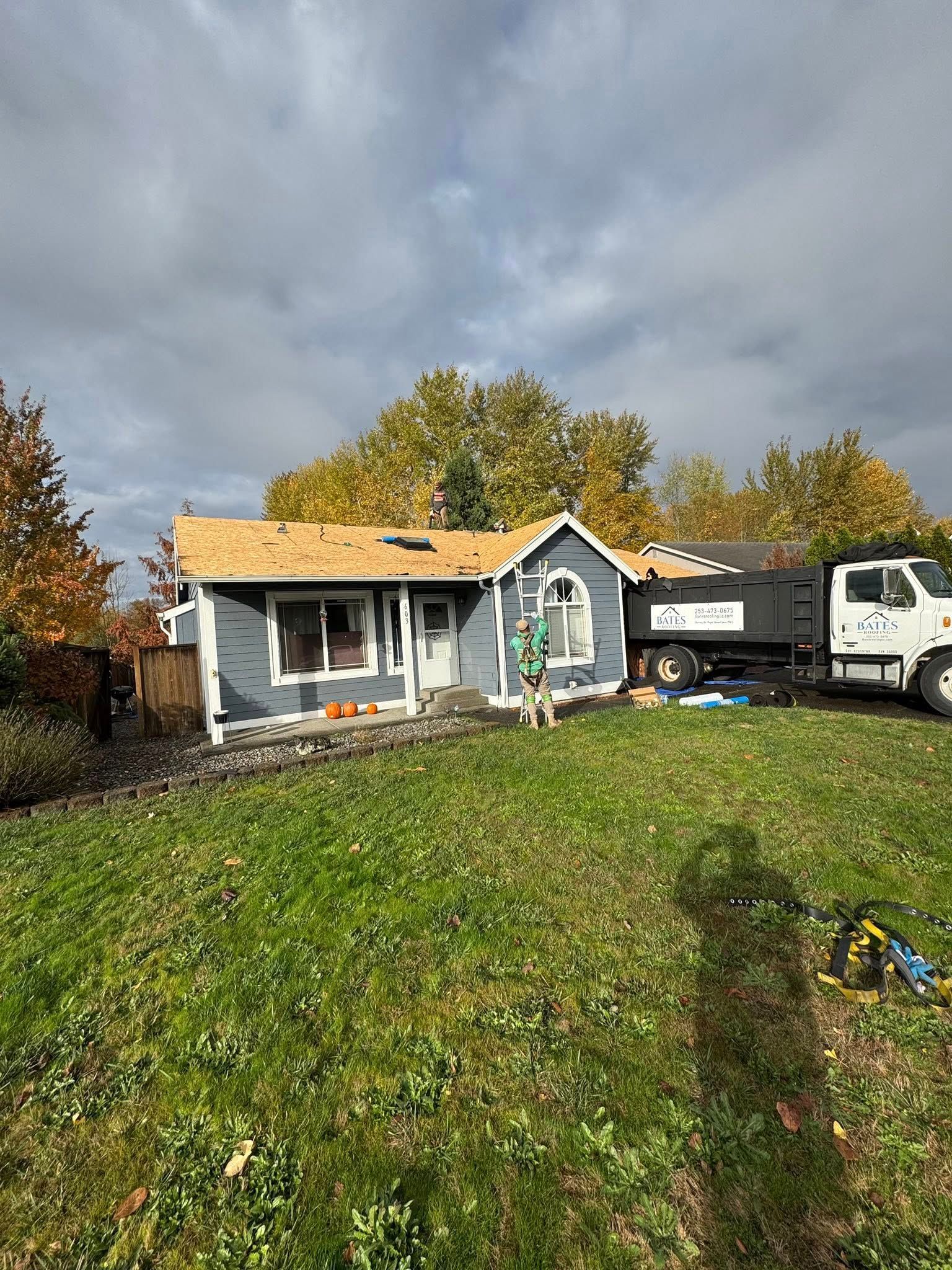 Blue house with partially removed roof, construction site, truck, and cloudy sky.