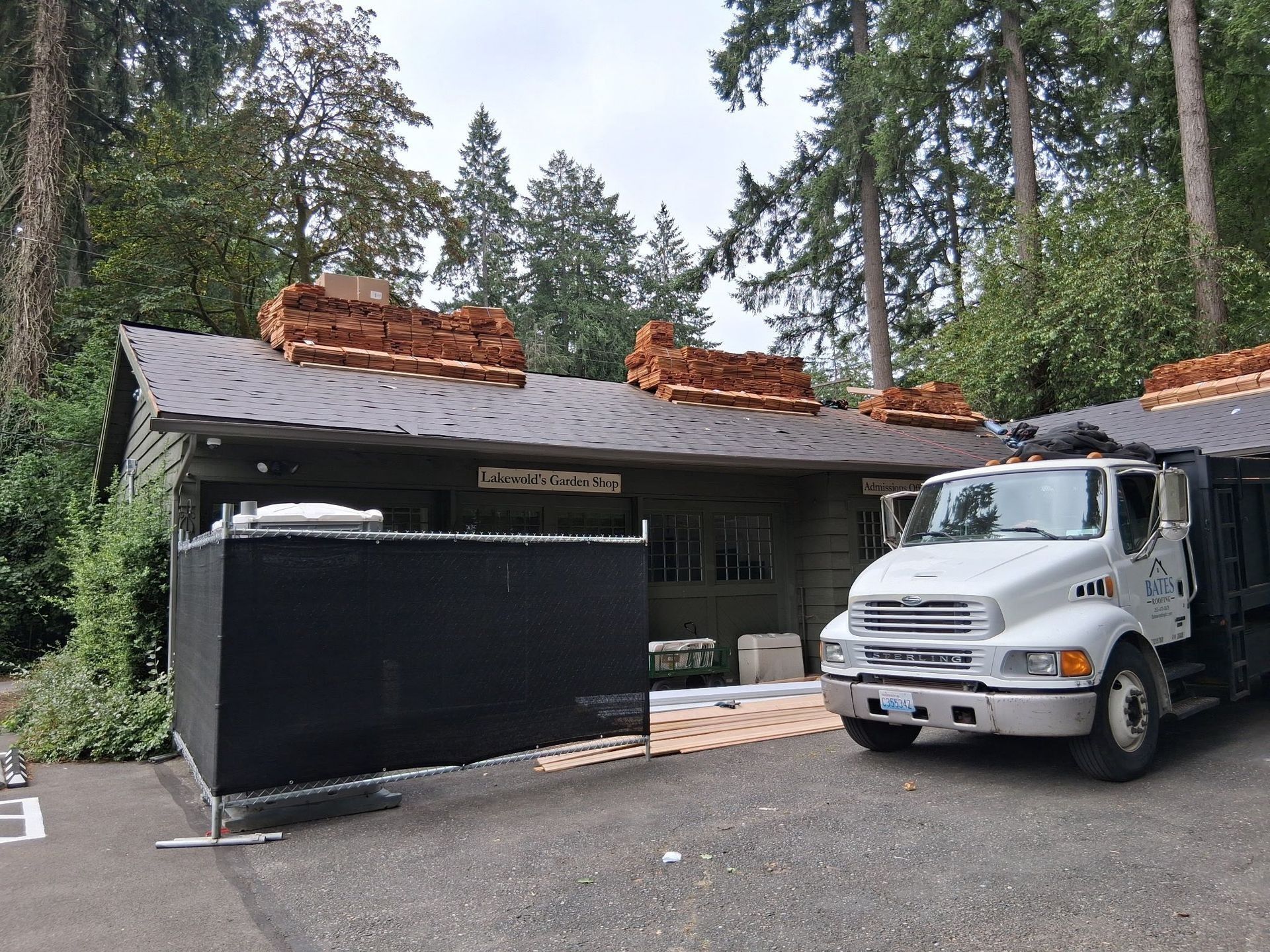 Building with a damaged roof and brick chimneys, a white dump truck parked nearby.