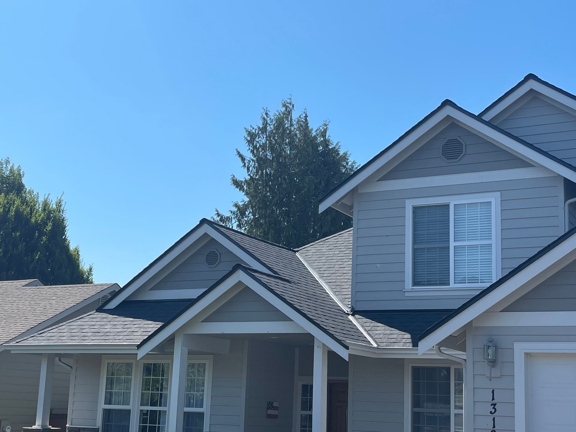 Houses with gray siding and dark roofs under a clear blue sky.