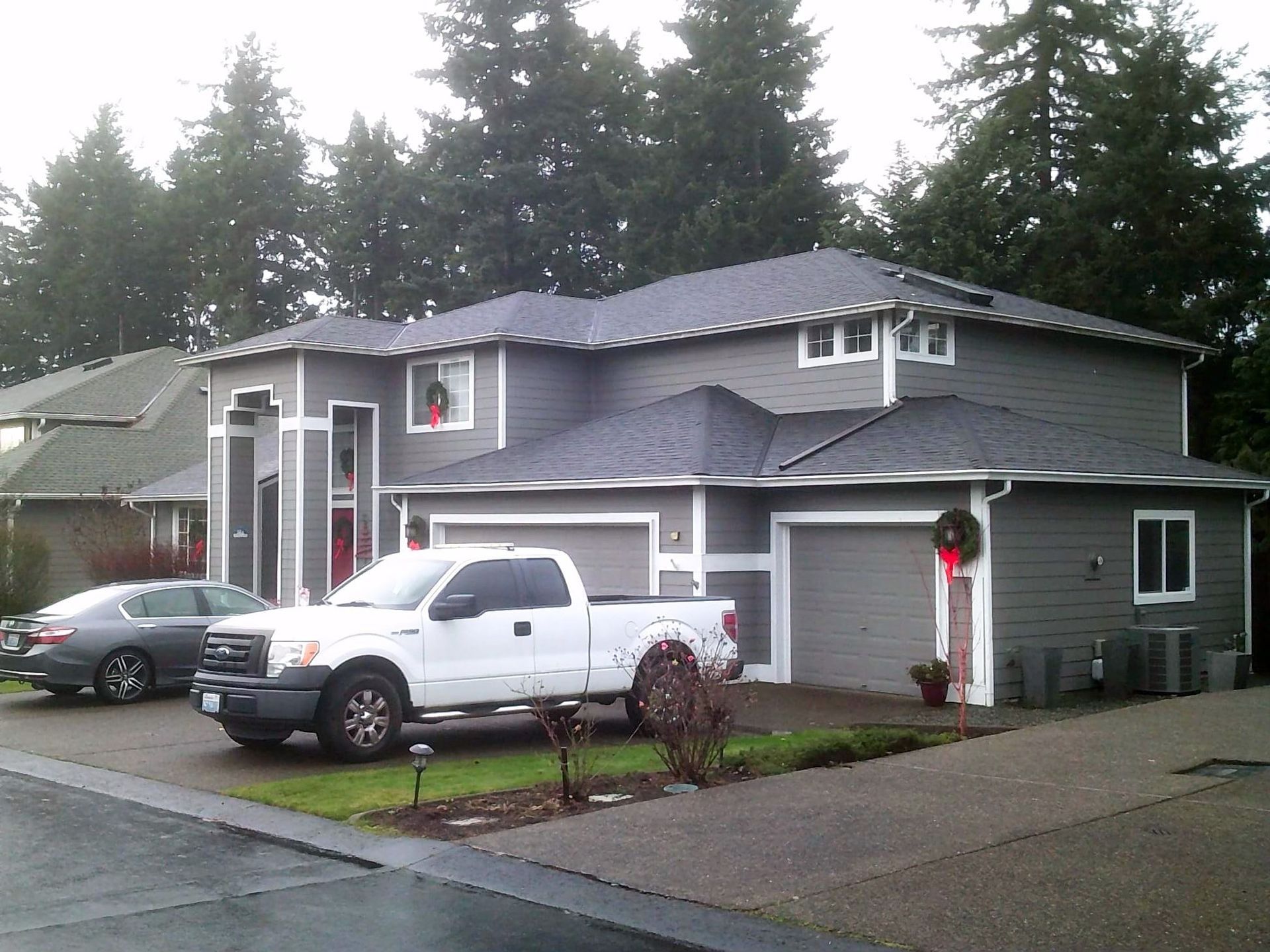 Gray two-story house with white trim and a white truck parked in the driveway.