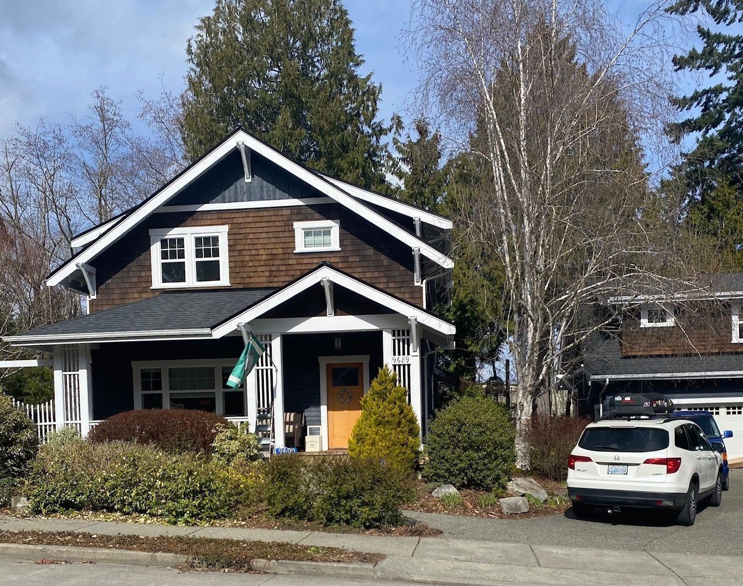 House with blue siding, brown roof, white trim, and a car parked in front.