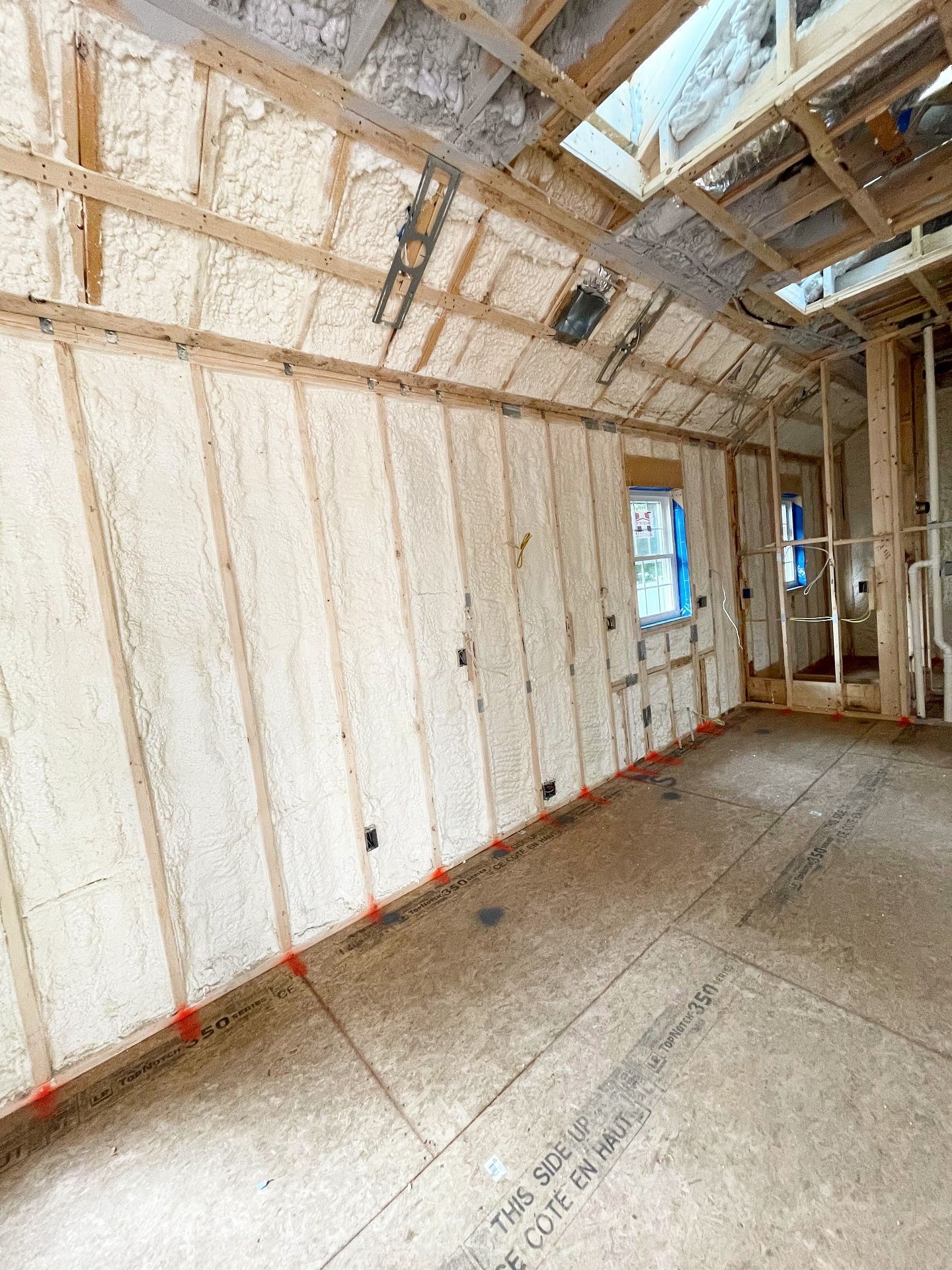 Interior framing of a room with spray foam insulation on the walls.