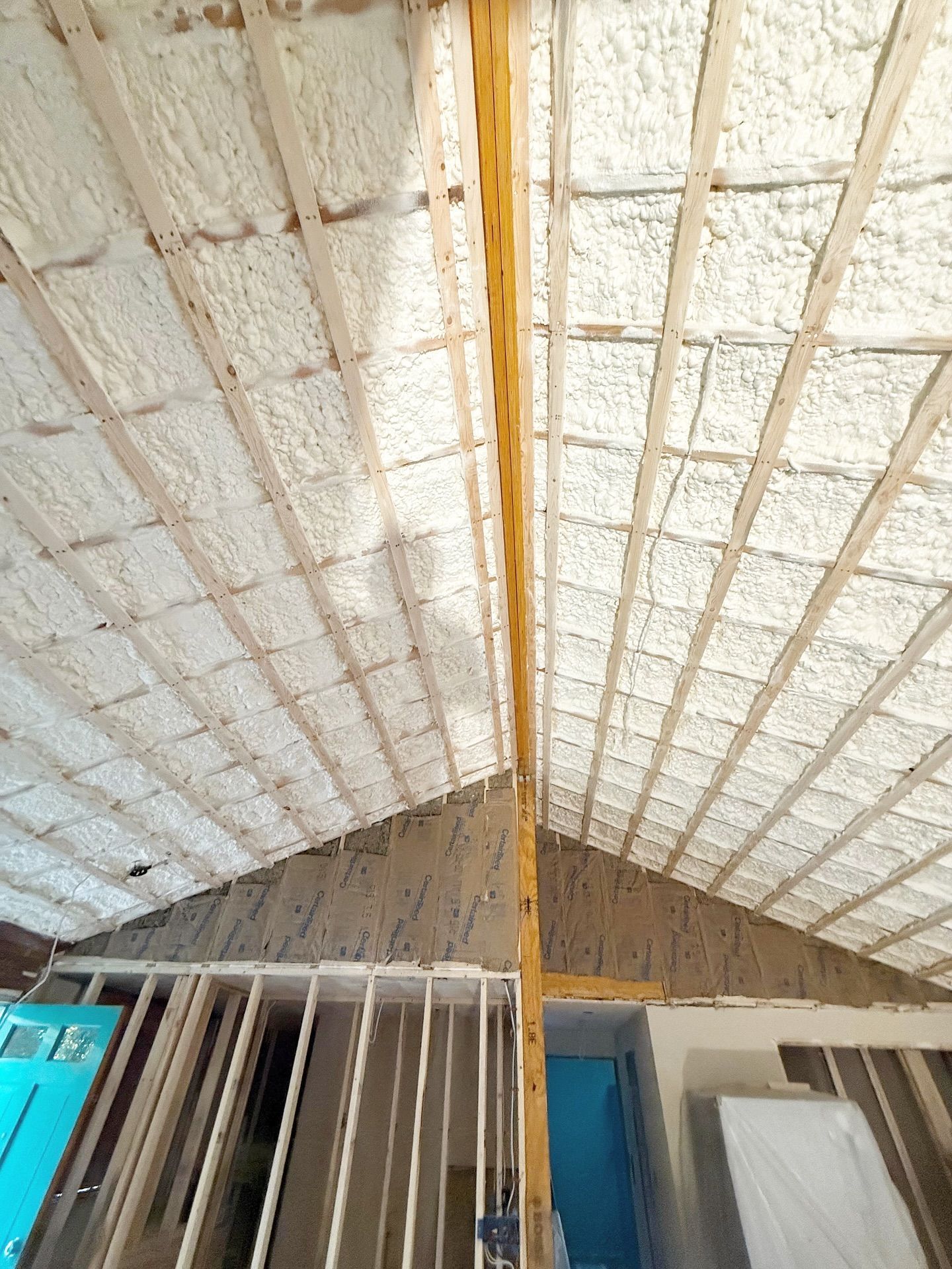Interior view of a partially constructed building with spray foam insulation on the sloped ceiling.